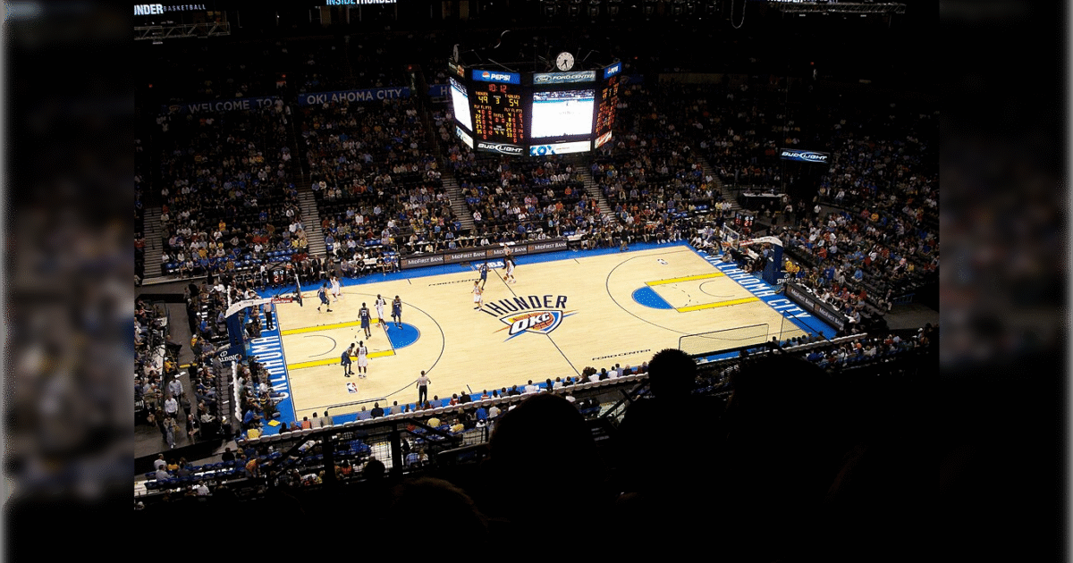 Oklahoma City Thunder basketball game in a packed arena with players on the court and a scoreboard displaying game details.
