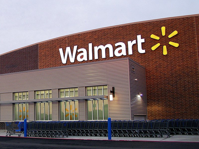 Exterior view of a Walmart store featuring the iconic logo and shopping carts lined up outside.