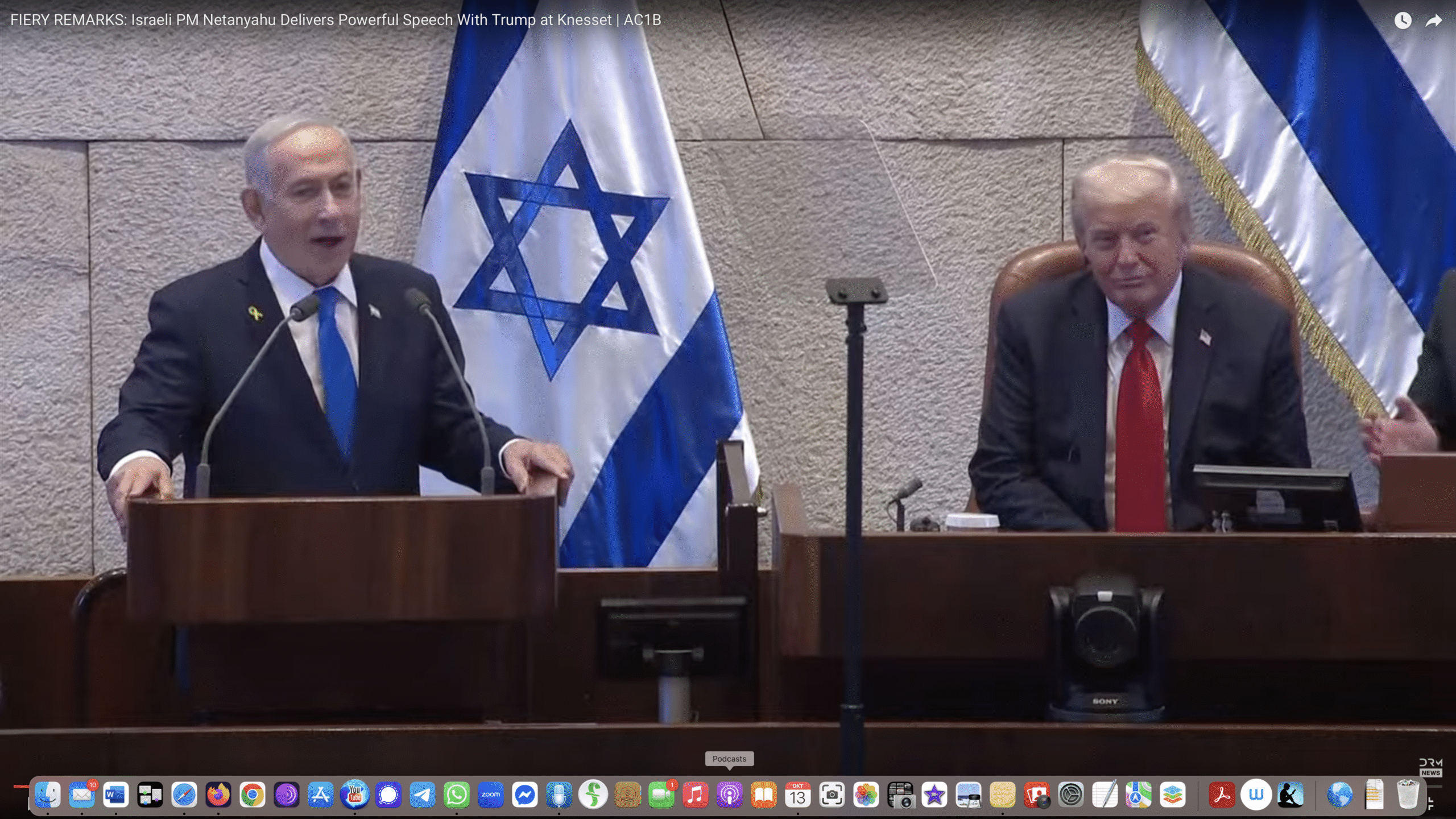 Israeli Prime Minister Netanyahu delivers a speech at the Knesset alongside former President Trump, with Israeli flags in the background.