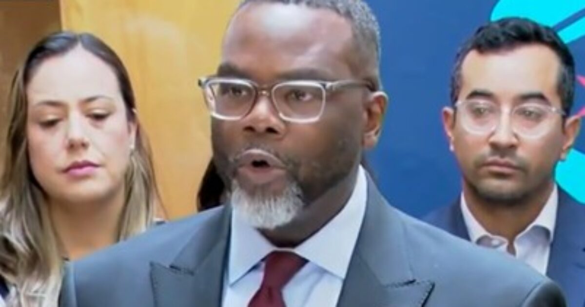 A man in a suit speaks at a press conference, flanked by two individuals, discussing important community issues.