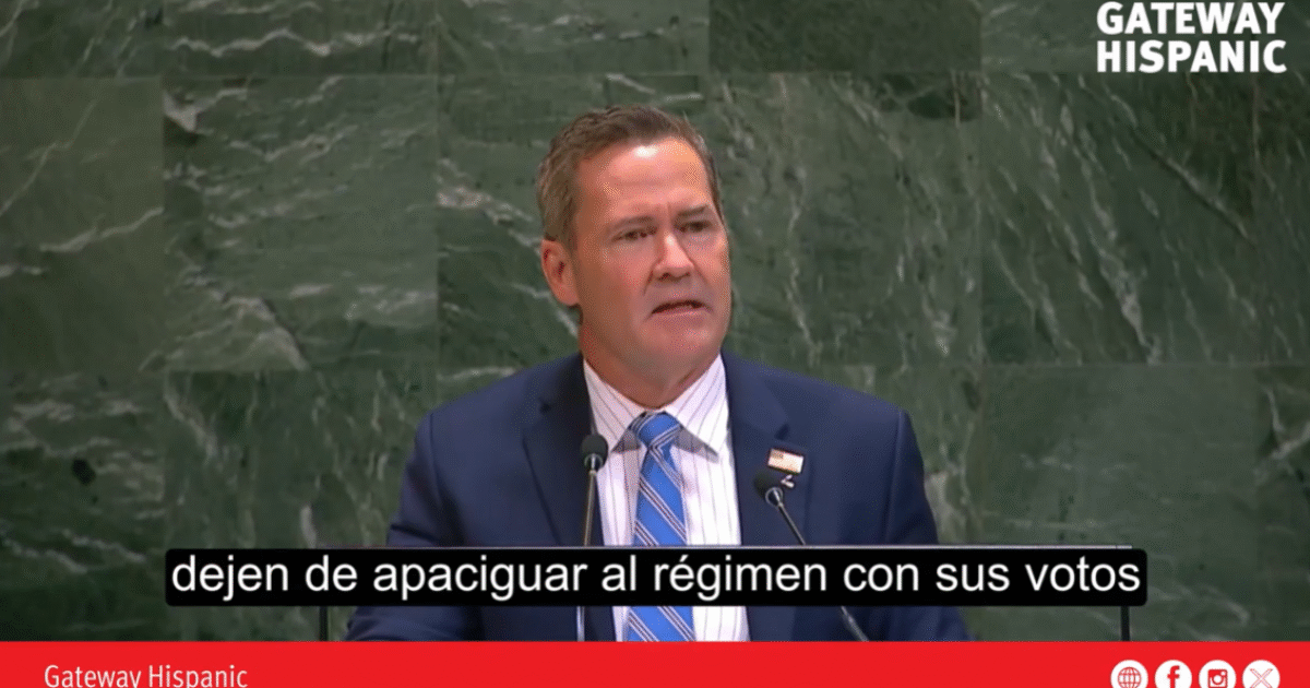 Speaker addressing an audience at a podium, emphasizing political engagement and the importance of voting against oppressive regimes.