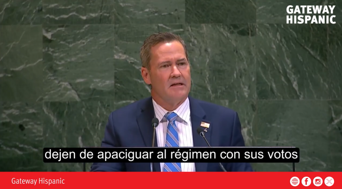 Speaker addressing an audience at a podium, emphasizing political engagement and the importance of voting against oppressive regimes.