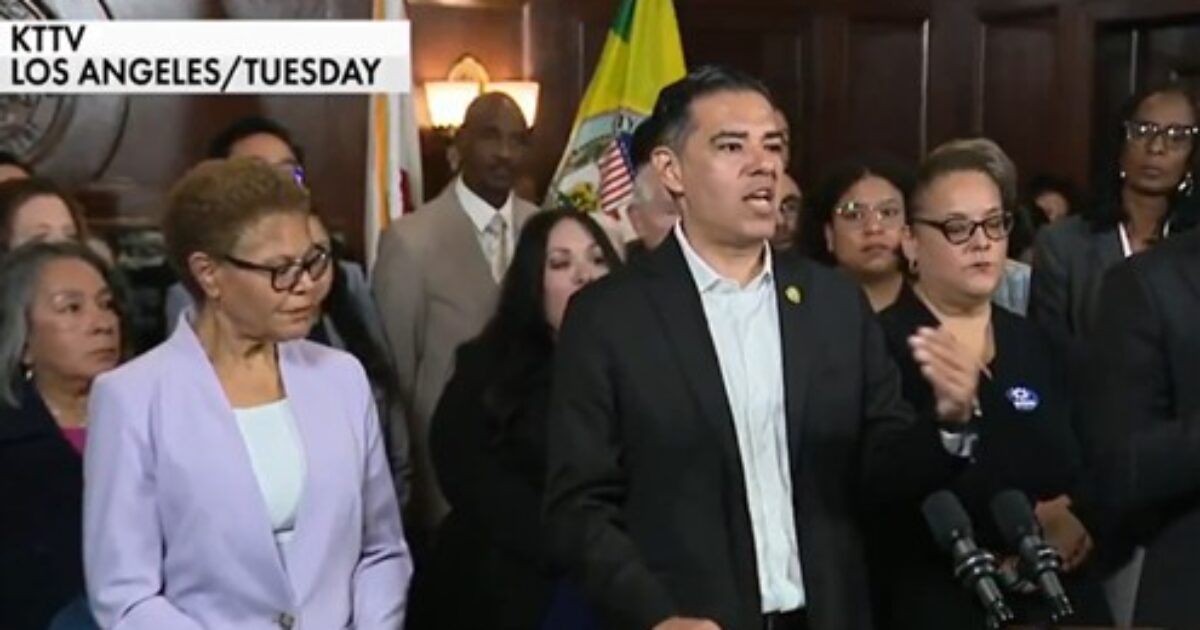 Press conference in Los Angeles featuring a diverse group of officials, with a speaker addressing issues while others listen attentively.