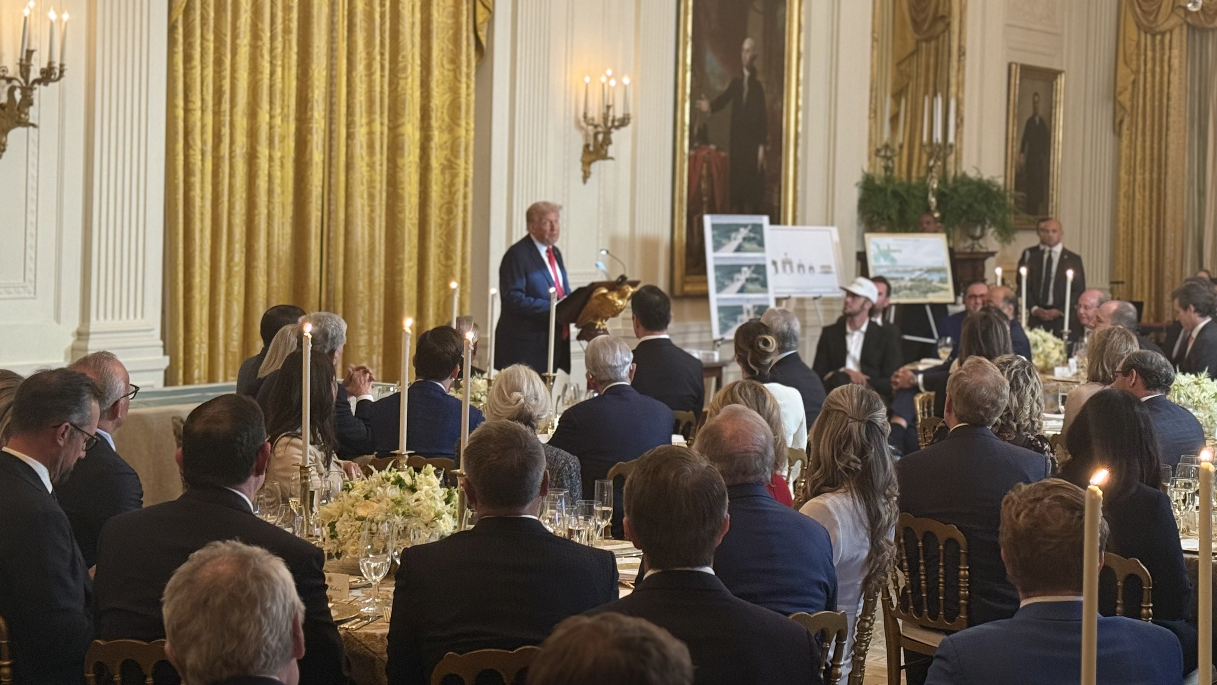 Donald Trump delivers a speech at a formal event in the White House, with attendees seated at elegantly decorated tables.