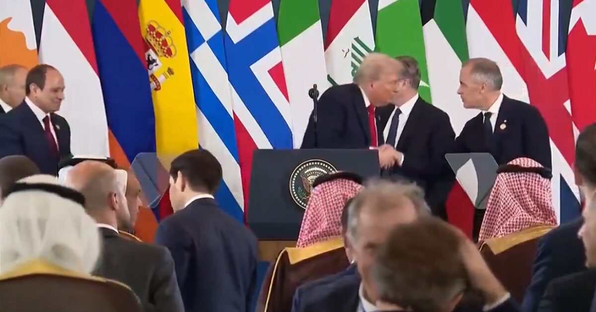 World leaders, including Donald Trump, engage in diplomatic discussions at a summit, surrounded by national flags representing various countries.