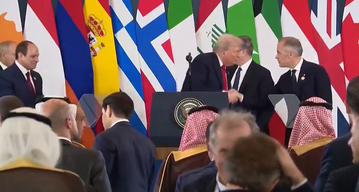 World leaders, including Donald Trump, engage in diplomatic discussions at a summit, surrounded by national flags representing various countries.