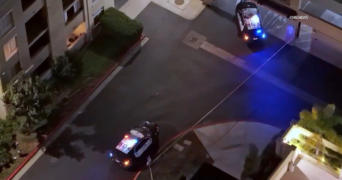 Police vehicles with flashing lights are stationed in a residential area, indicating a potential investigation or emergency situation.