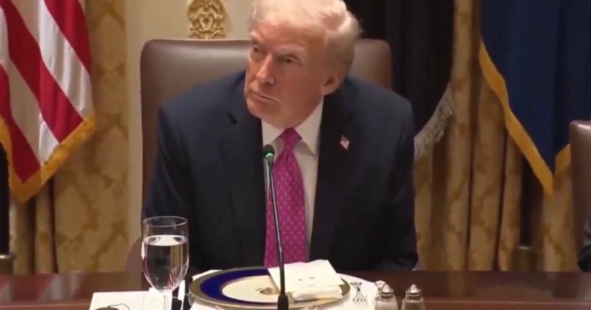 Donald Trump seated at a formal dining table with a glass of water and a plate, during an official meeting.
