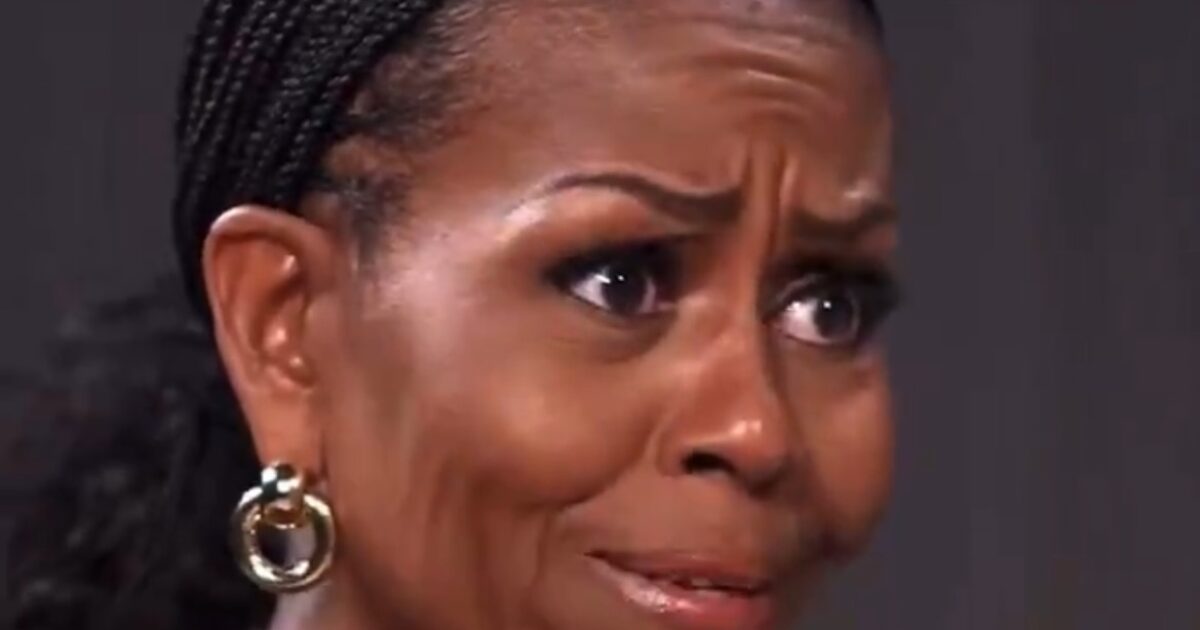 Close-up of a woman with braided hair, expressing emotion with a concerned facial expression, wearing large hoop earrings and a green top.