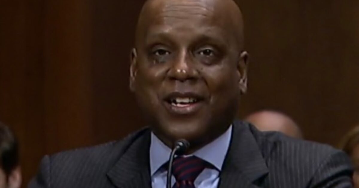 A smiling man in a suit speaks at a formal event, showcasing a confident demeanor during a Senate hearing.