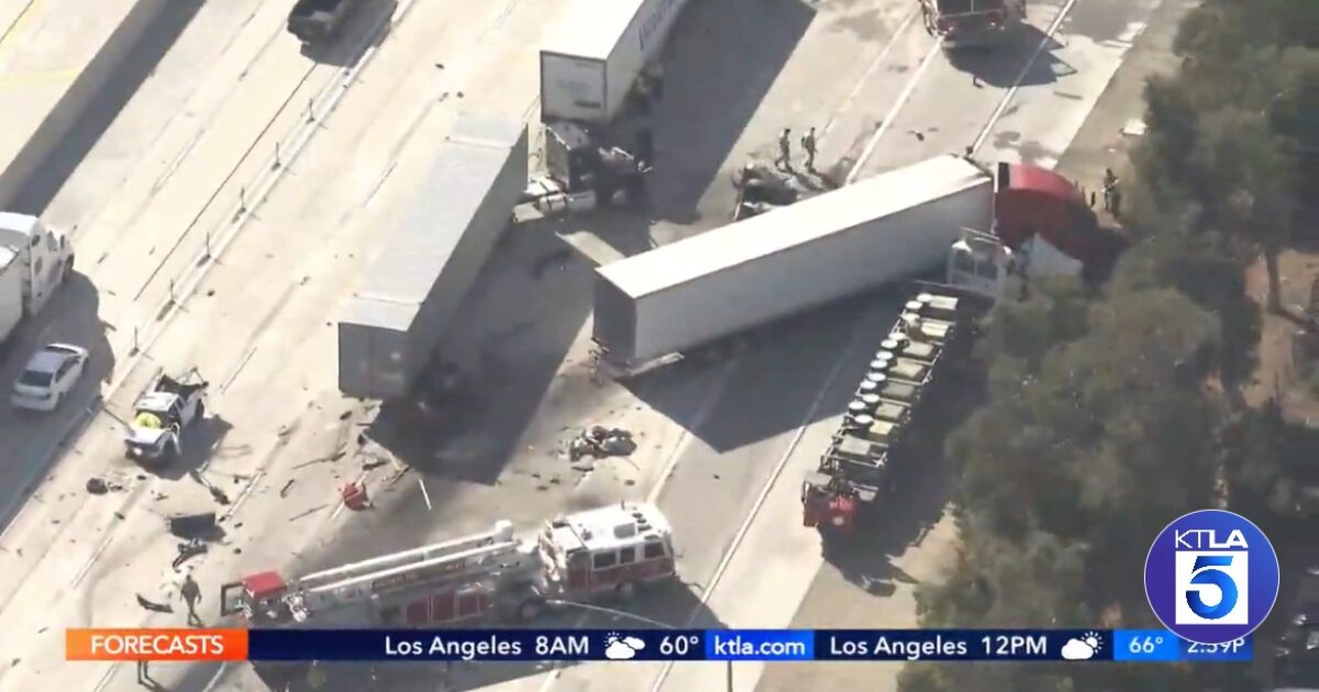 Aerial view of a multi-vehicle accident on a highway, featuring overturned trucks, debris, and emergency responders at the scene.