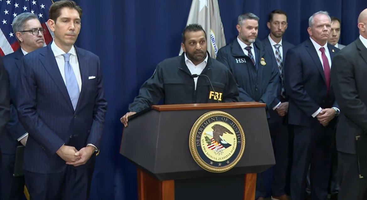 FBI officials hold a press conference with law enforcement representatives, discussing recent operations and updates on criminal investigations.