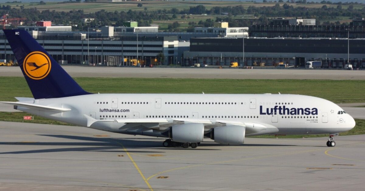 Lufthansa A380 aircraft taxiing on the runway, showcasing its distinctive livery and large size against a backdrop of an airport terminal.
