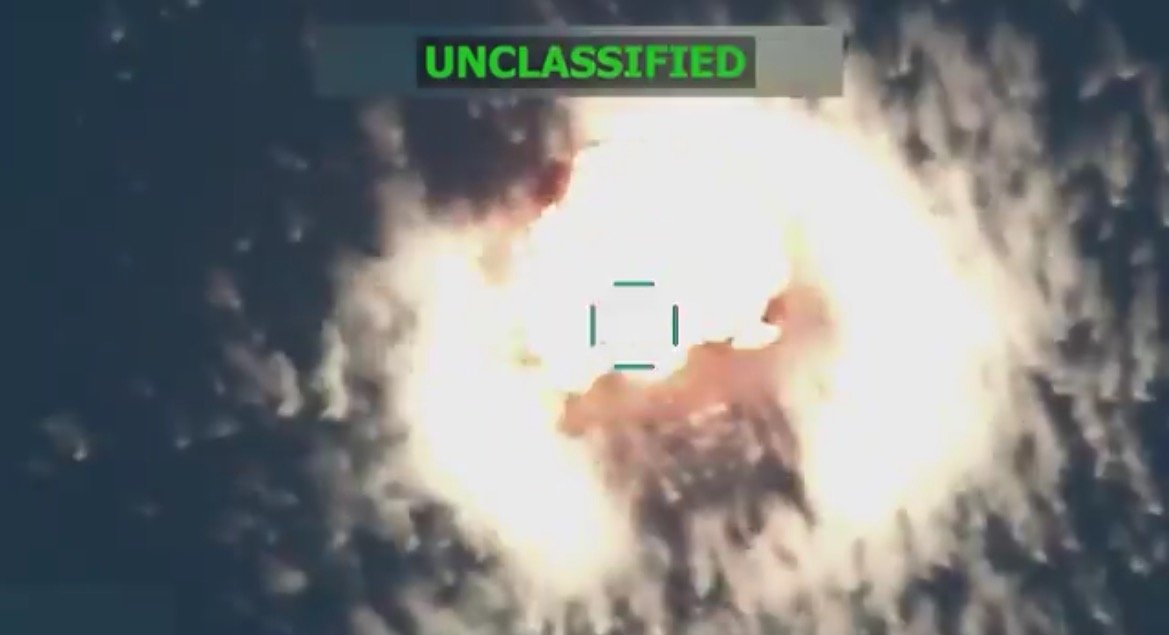 Aerial view of an explosion captured in an unclassified military video, showcasing a bright fireball against a dark background.