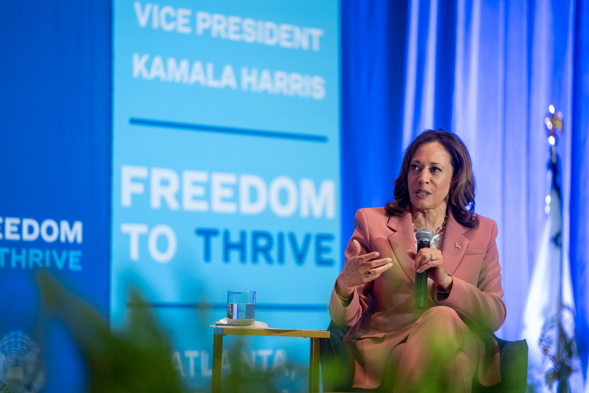 Vice President Kamala Harris speaking at the Freedom to Thrive event in Atlanta, discussing key issues while seated with a microphone.