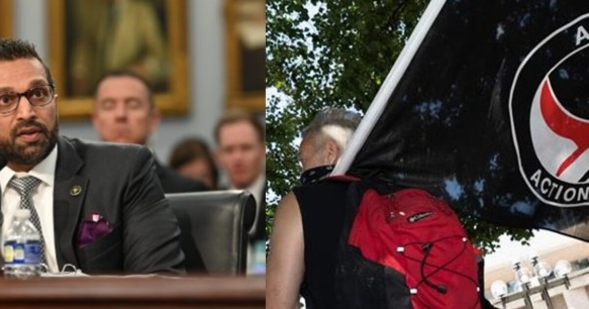 Image shows a congressional hearing with a speaker at a table and a protester holding an Antifa flag, illustrating political discourse and activism.