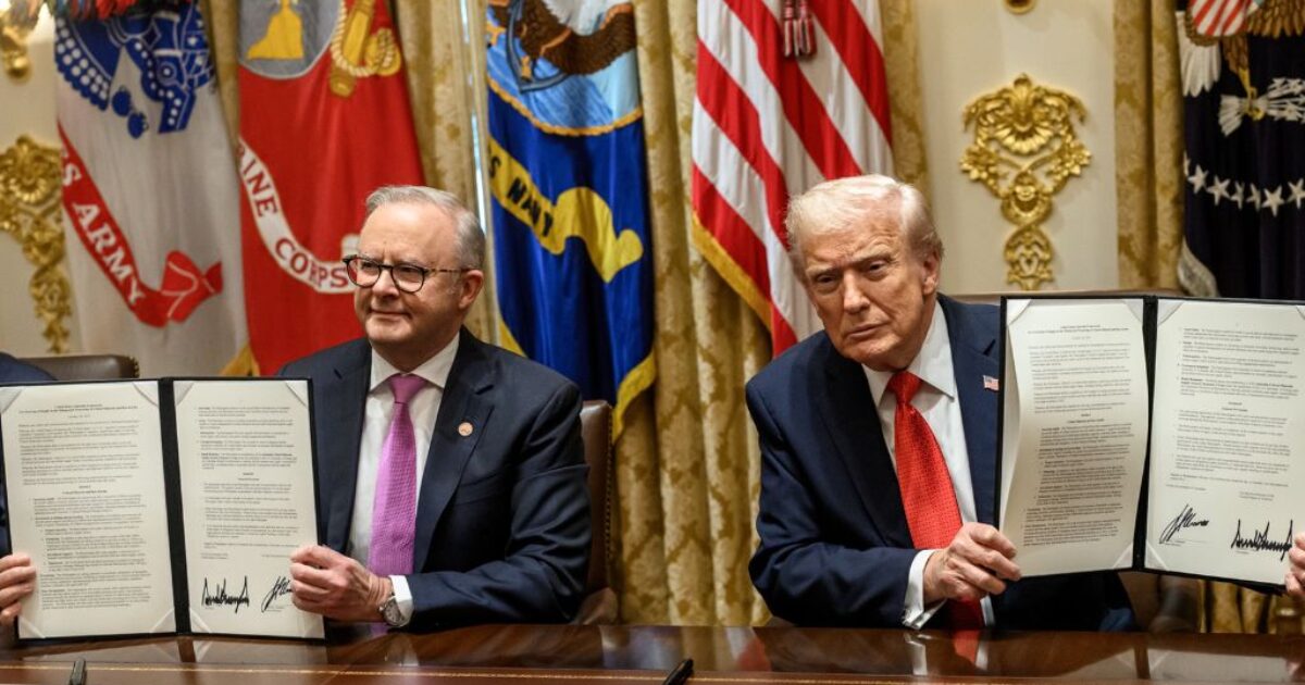 Australian Prime Minister and U.S. President sign a formal agreement, showcasing their commitment to bilateral relations in a ceremonial setting.