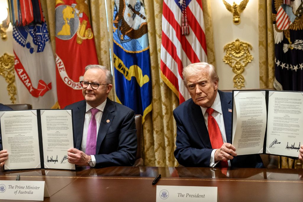 Australian Prime Minister and U.S. President sign a formal agreement, showcasing their commitment to bilateral relations in a ceremonial setting.