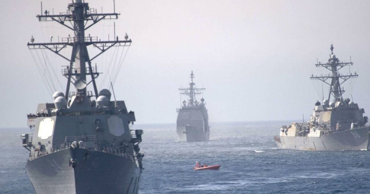 Three naval ships navigate through calm waters, accompanied by a small boat, showcasing maritime operations and naval strength.