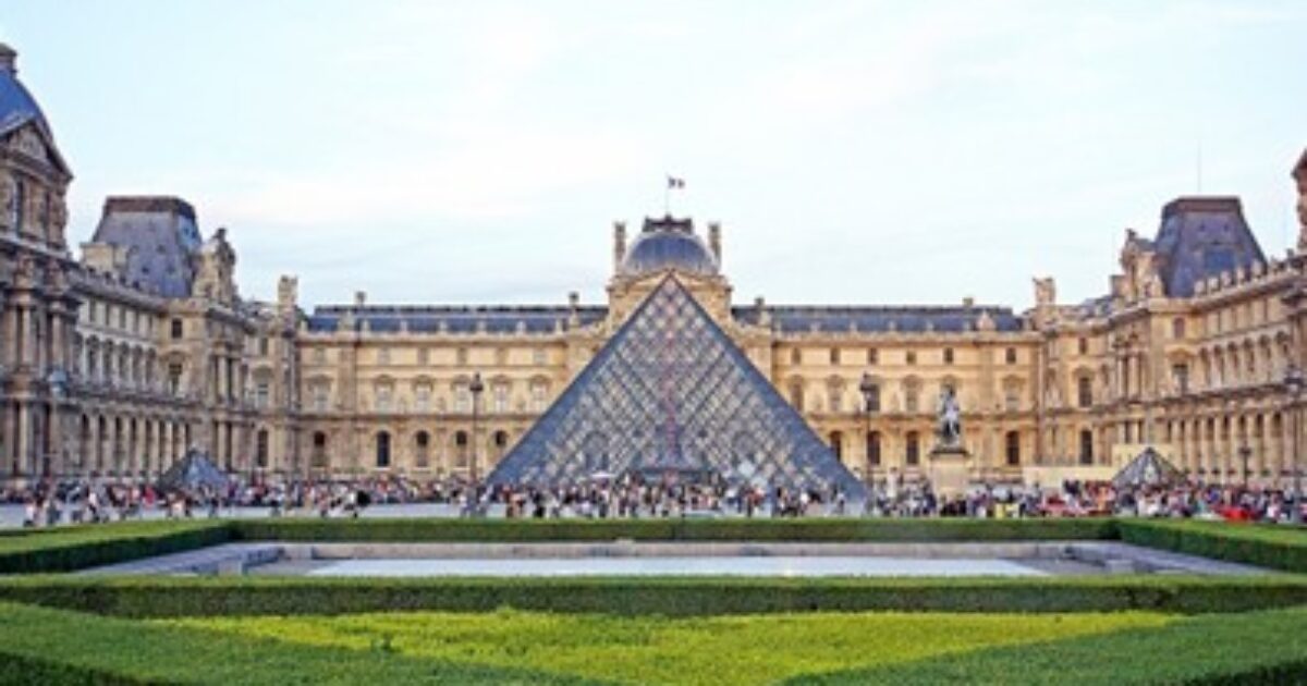 Louvre Museum with iconic glass pyramid, surrounded by historic architecture and lush gardens, attracting numerous visitors in Paris, France.