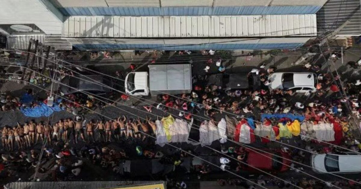 Aerial view of a crowded street scene with people lying on the ground and colorful fabrics, highlighting a significant public gathering or event.