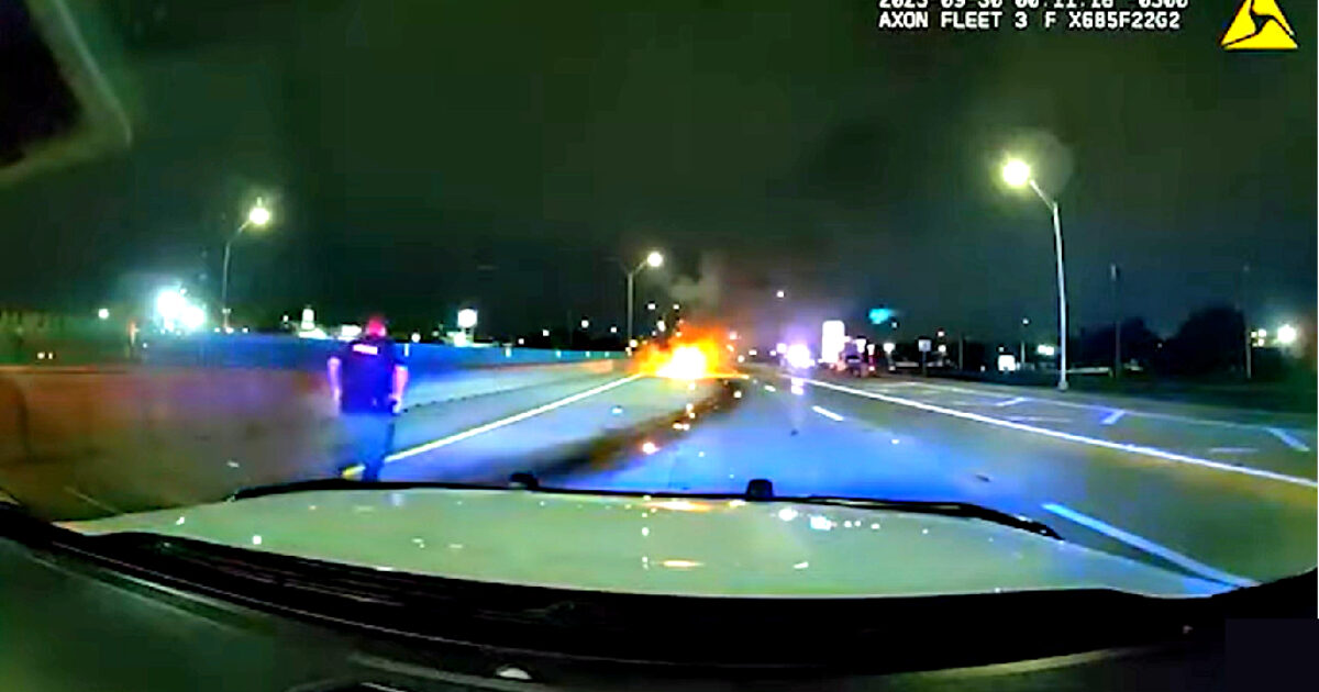 Emergency response to a vehicle fire on a highway at night, with police officers approaching the scene.