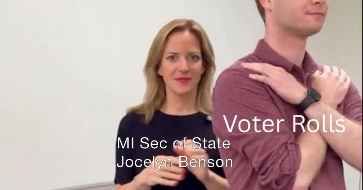 Michigan Secretary of State Jocelyn Benson discusses voter rolls with a colleague in an office setting, emphasizing election integrity and voter registration processes.
