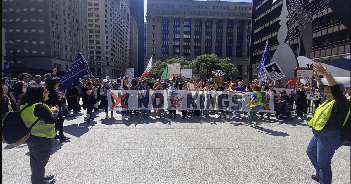 Protesters gather in a city square holding signs and banners, including one that reads "No Kings," advocating for social change and justice.
