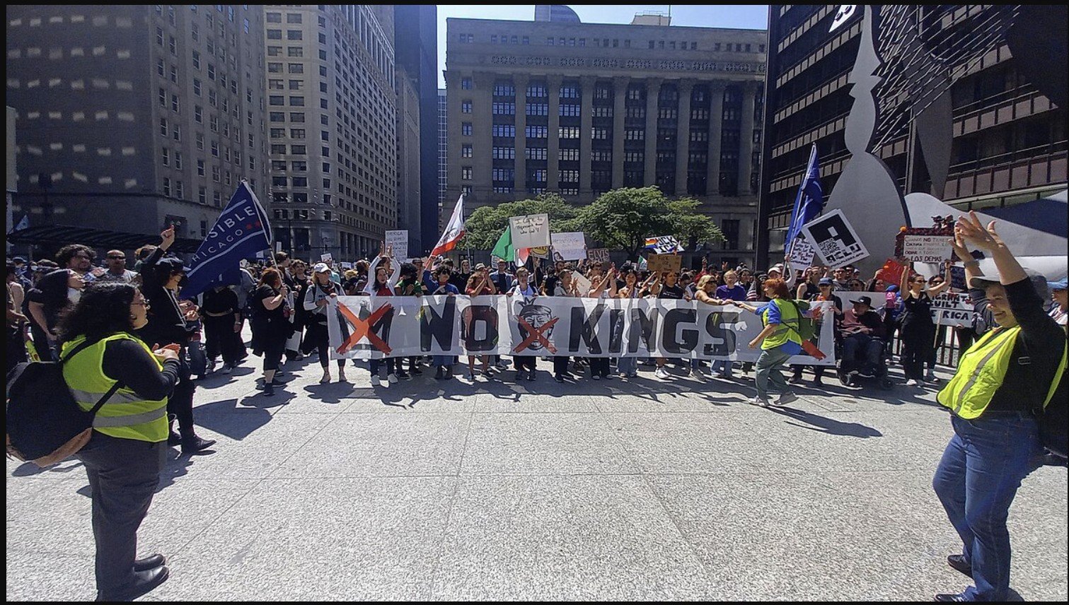 Protesters gather in a city square holding signs and banners, including one that reads "No Kings," advocating for social change and justice.
