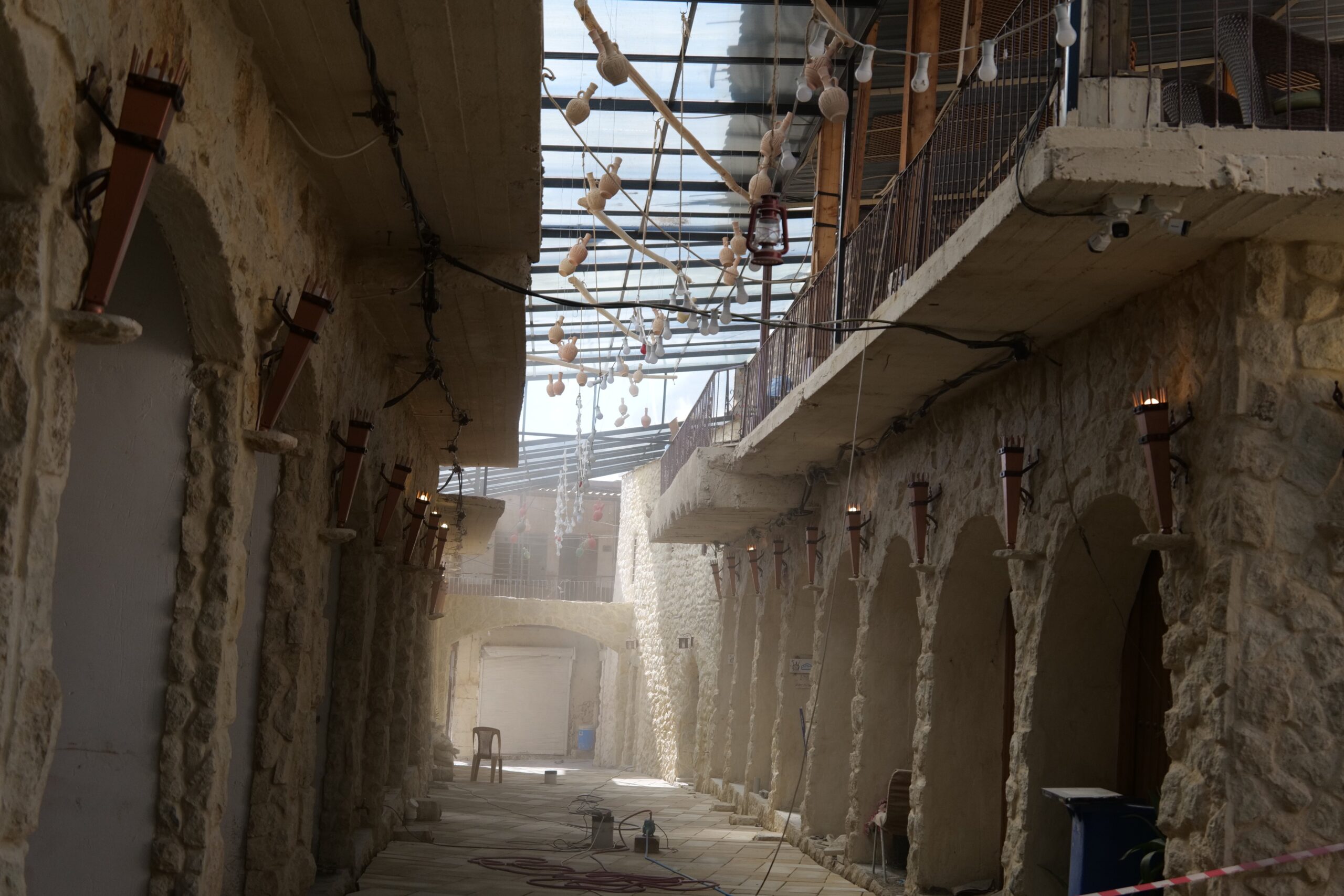 Renovated stone corridor with decorative lanterns and hanging elements, showcasing a blend of rustic architecture and modern design.
