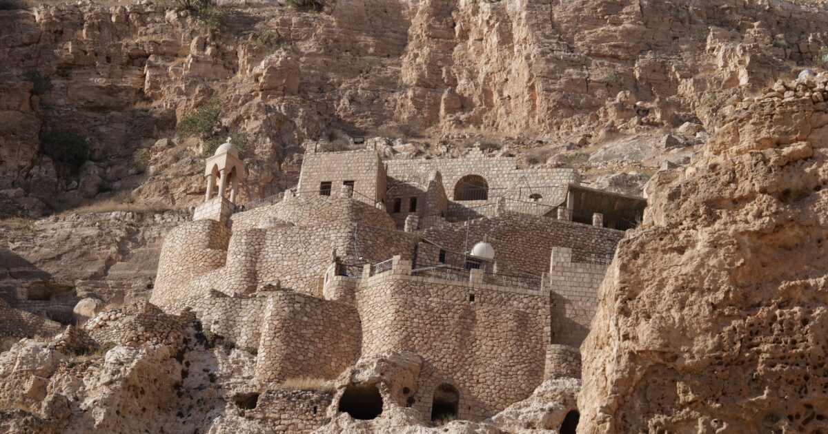 Ancient stone structures built into a rocky hillside, showcasing historical architecture and natural landscape in a desert environment.