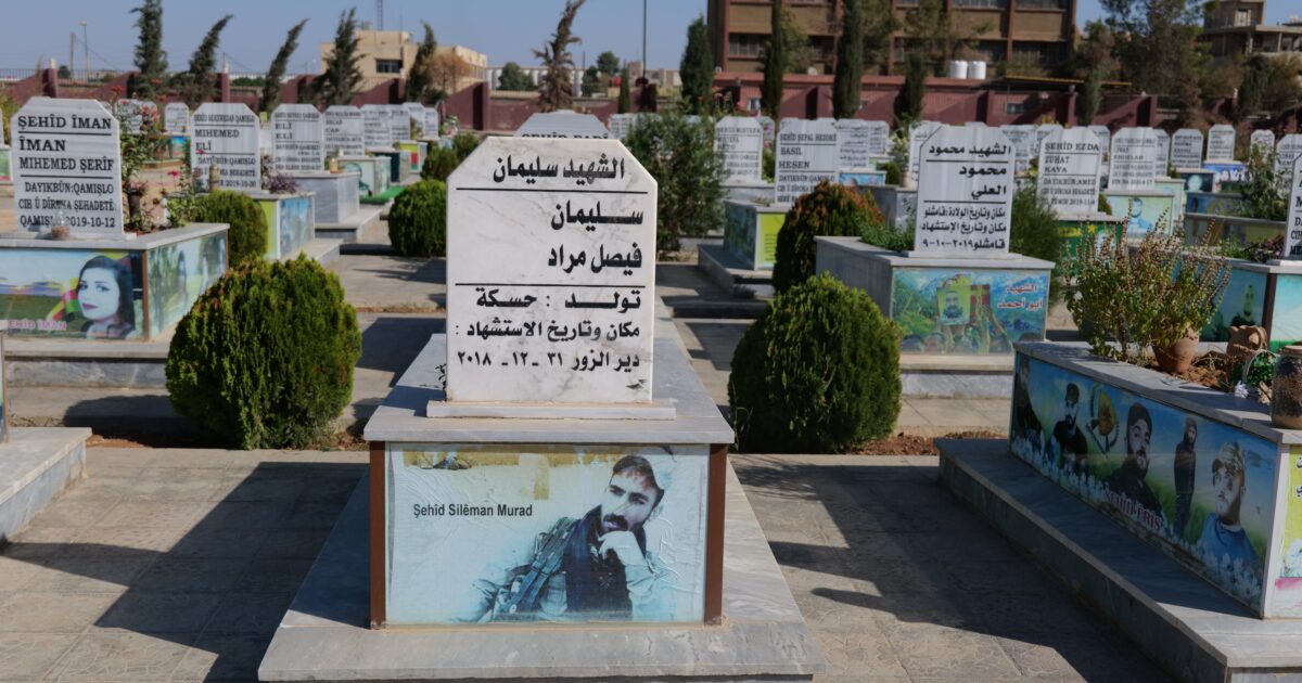 Gravestones in a cemetery featuring personalized memorials and photographs, honoring individuals who have passed away, with a clear blue sky in the background.