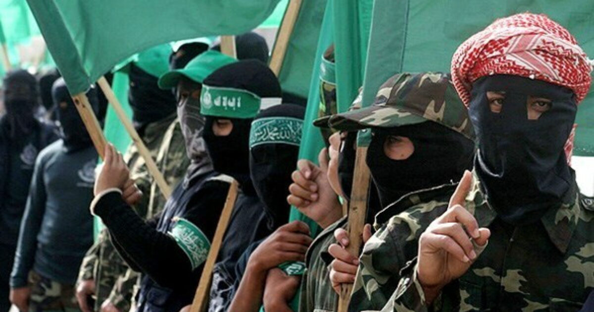 Masked individuals in military attire hold green flags during a demonstration, symbolizing their political affiliation and solidarity.