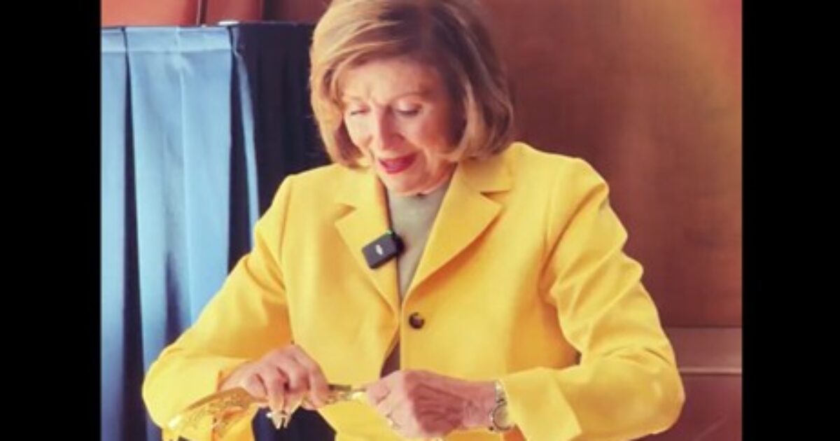 Woman in a yellow blazer carefully unwrapping a decorative item at a formal event.