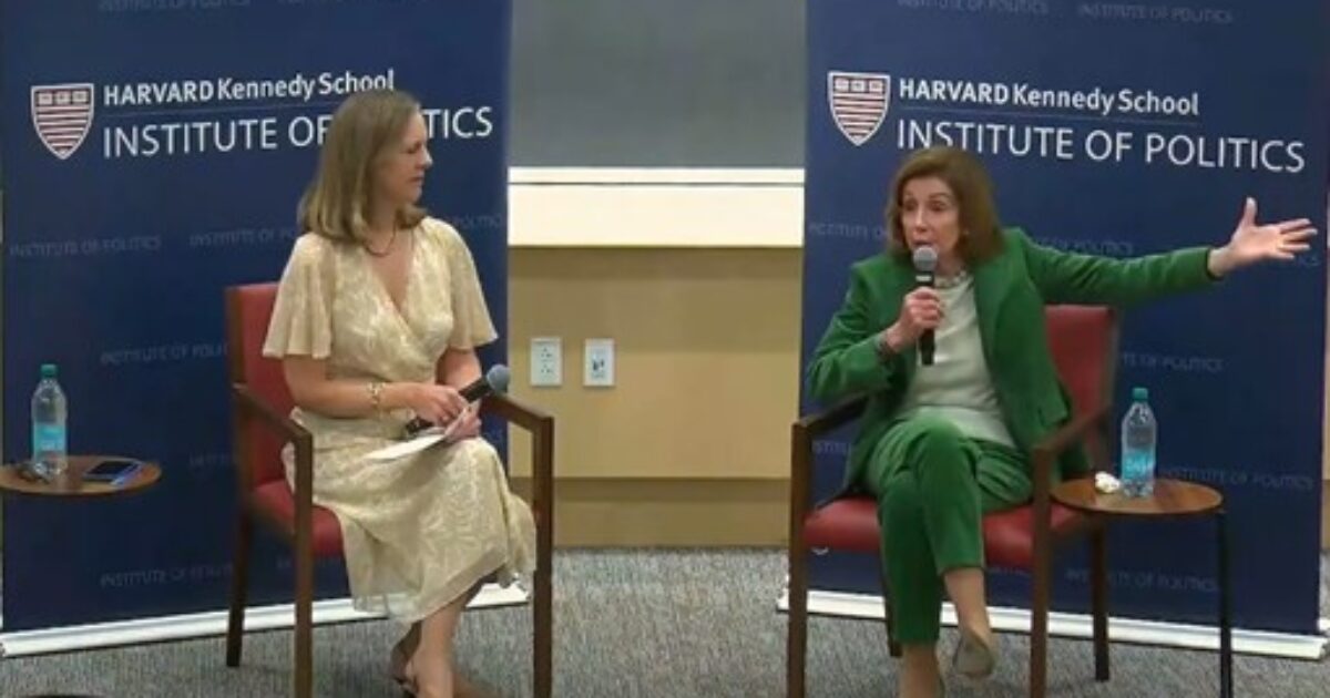 Discussion at Harvard Kennedy School featuring a speaker in green attire and a moderator in a light dress, both engaged in a political dialogue.