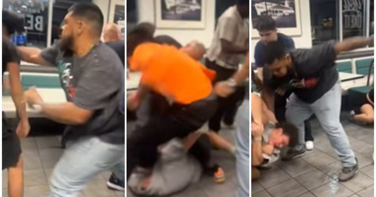 A chaotic scene of multiple individuals engaged in a physical altercation inside a fast-food restaurant.