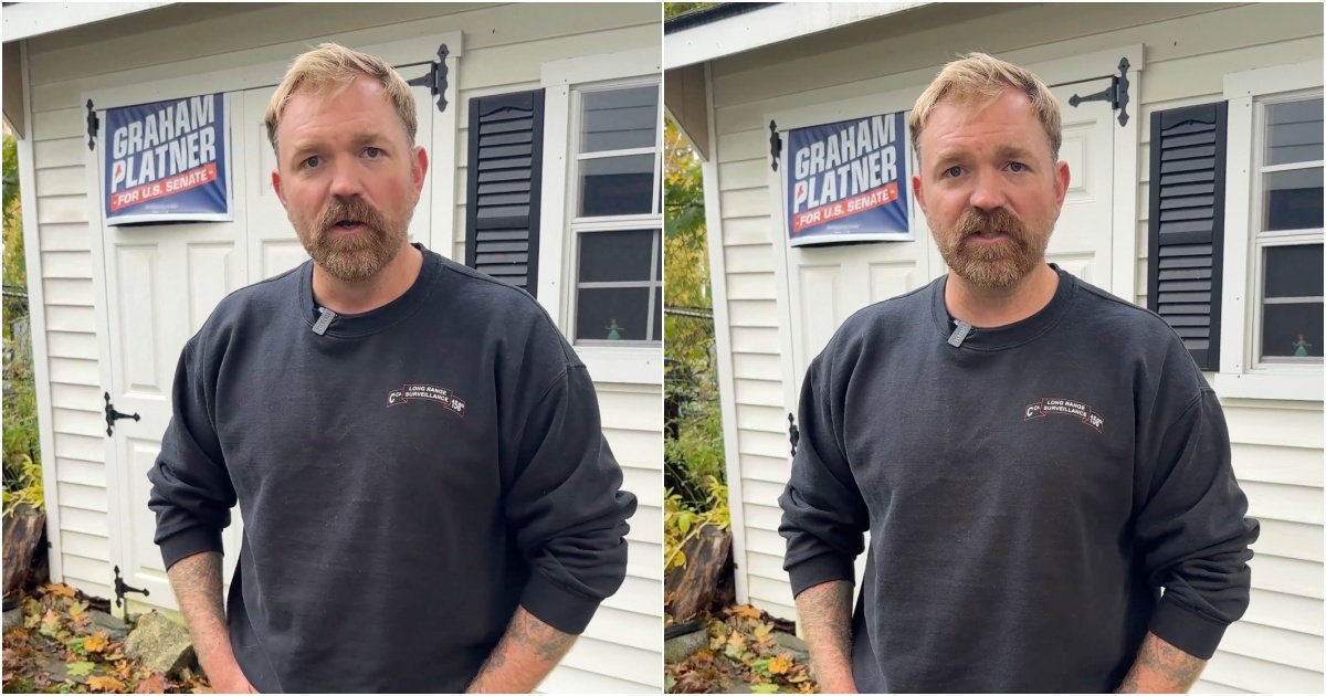 Man with a beard wearing a black sweatshirt stands outside a building with a sign for Graham Platner's U.S. Senate campaign.