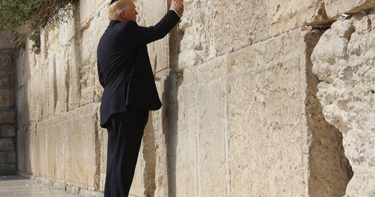 Former U.S. President visiting the Western Wall in Jerusalem, placing a note in the cracks of the ancient stone.