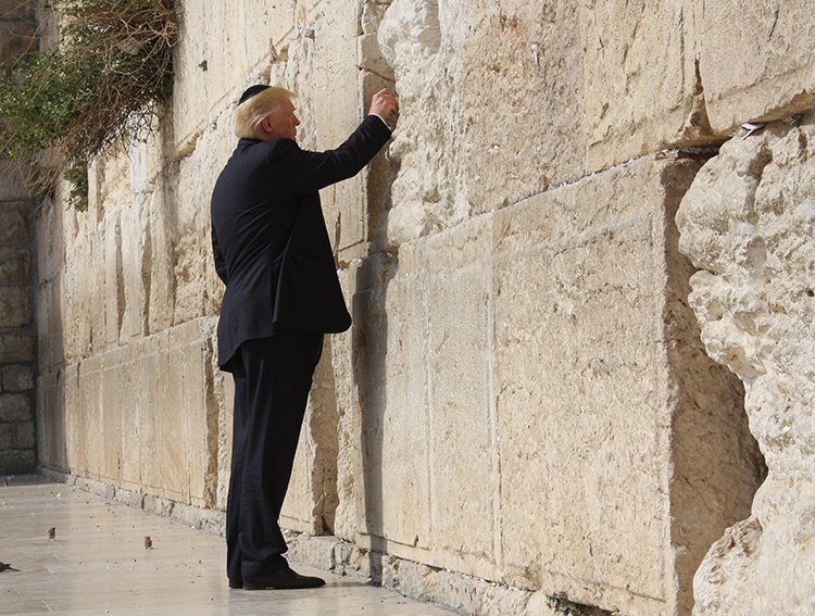 Former U.S. President visiting the Western Wall in Jerusalem, placing a note in the cracks of the ancient stone.