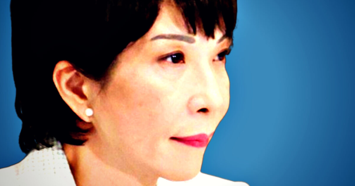 Close-up portrait of a woman with short dark hair and pearl earrings, set against a blue background, conveying a thoughtful expression.
