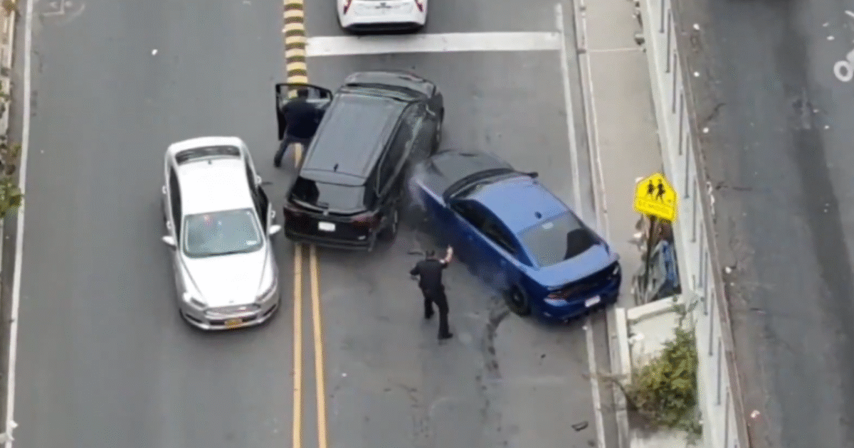 Police officer intervenes at the scene of a car accident involving three vehicles on a city street.