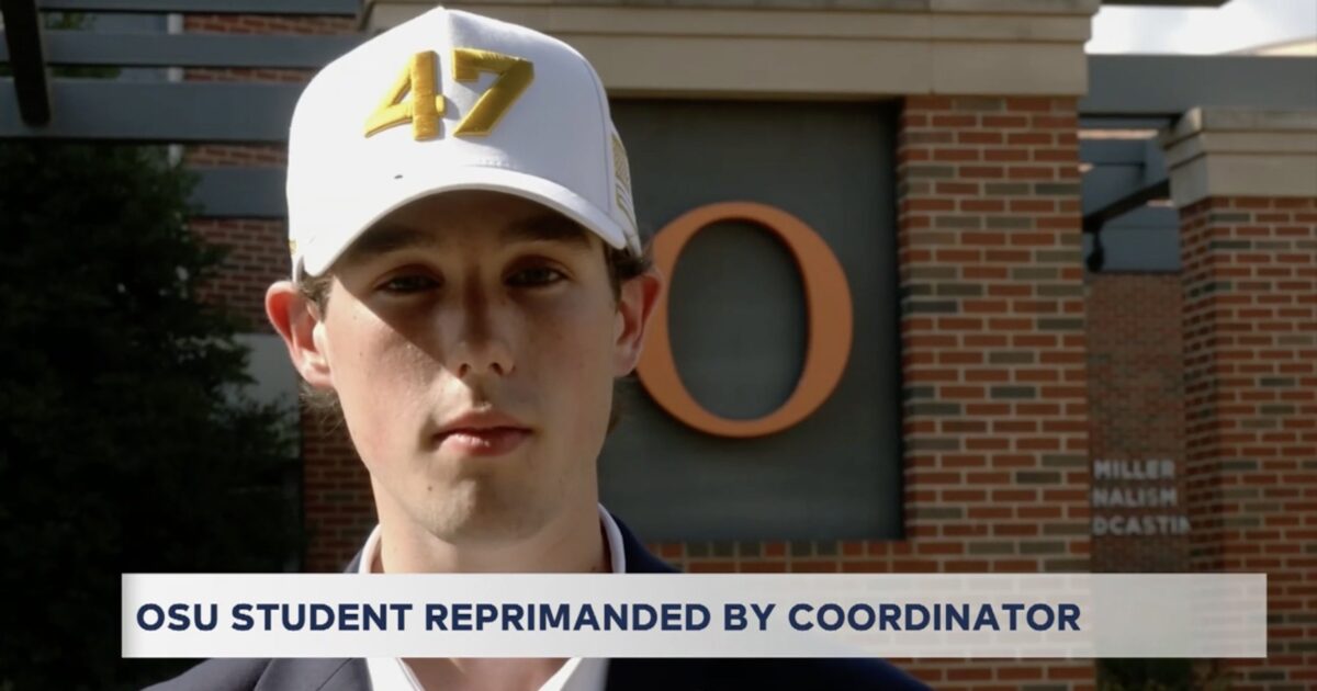 OSU student wearing a white cap with the number 47 stands in front of a university building, discussing a recent reprimand by a coordinator.
