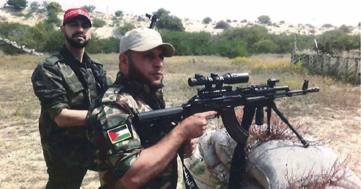 Two armed men in military camouflage pose with rifles in a grassy outdoor setting, highlighting a conflict or militia theme.