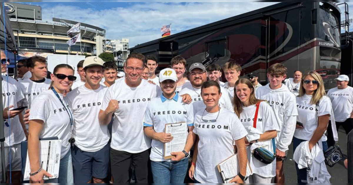 Group of people wearing matching "FREEDOM" t-shirts at a sports event, smiling and posing for a photo in front of a stadium.