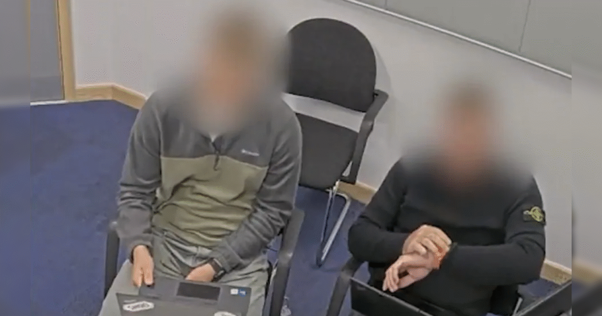 Two individuals sitting in a conference room, focused on laptops, with blurred faces for privacy.
