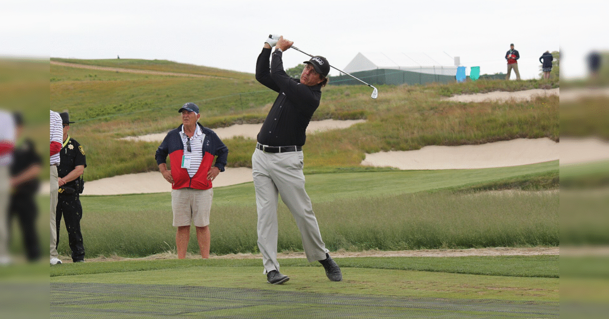 Golfer swinging a club on the course with spectators and security in the background, showcasing a competitive golf event.
