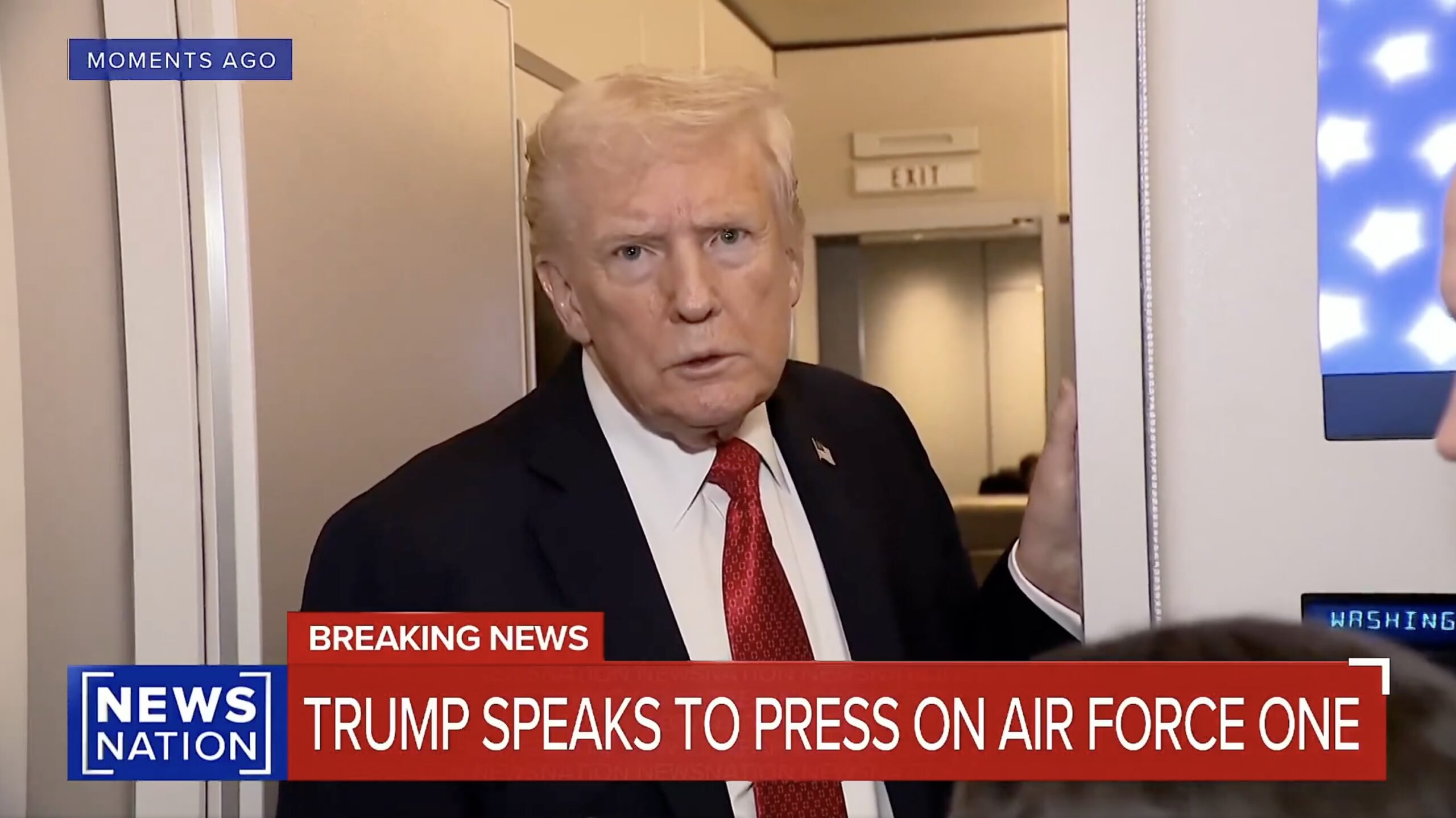 Donald Trump addressing the press on Air Force One, with a serious expression and a backdrop of the aircraft's interior.