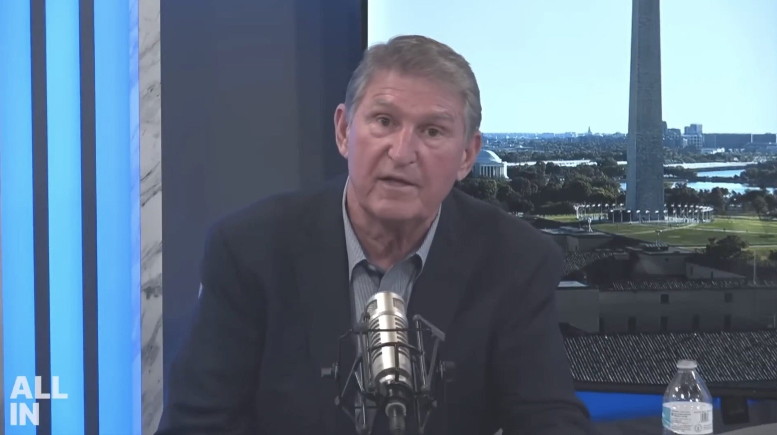Joe Manchin speaking during a podcast episode with the Washington Monument visible in the background, highlighting political discussions.