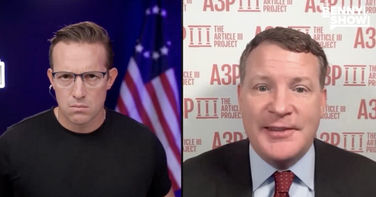 Two men engaged in a serious discussion on a video call, with one wearing glasses and a black shirt, and the other in a suit against a backdrop promoting The Article III Project.