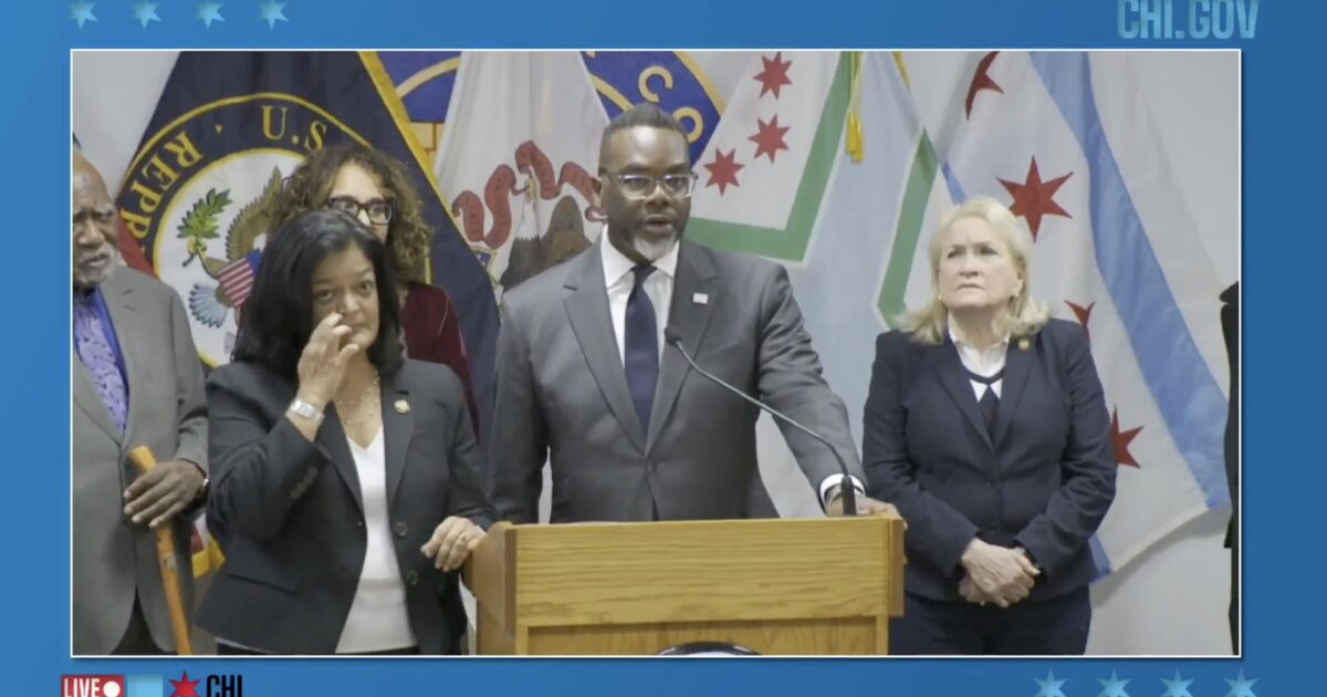 Press conference featuring Chicago officials discussing community initiatives, with multiple flags in the background and speakers at a podium.